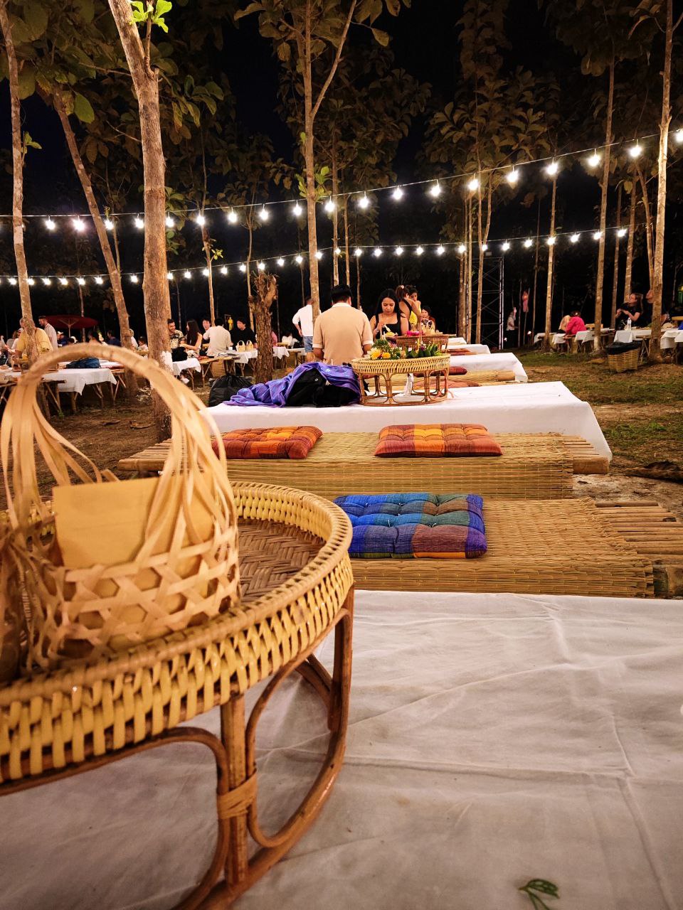 Cena tradizionale al festival di Chiang Mai, con piatti vegetali serviti su tavolini tipici in un'atmosfera suggestiva.