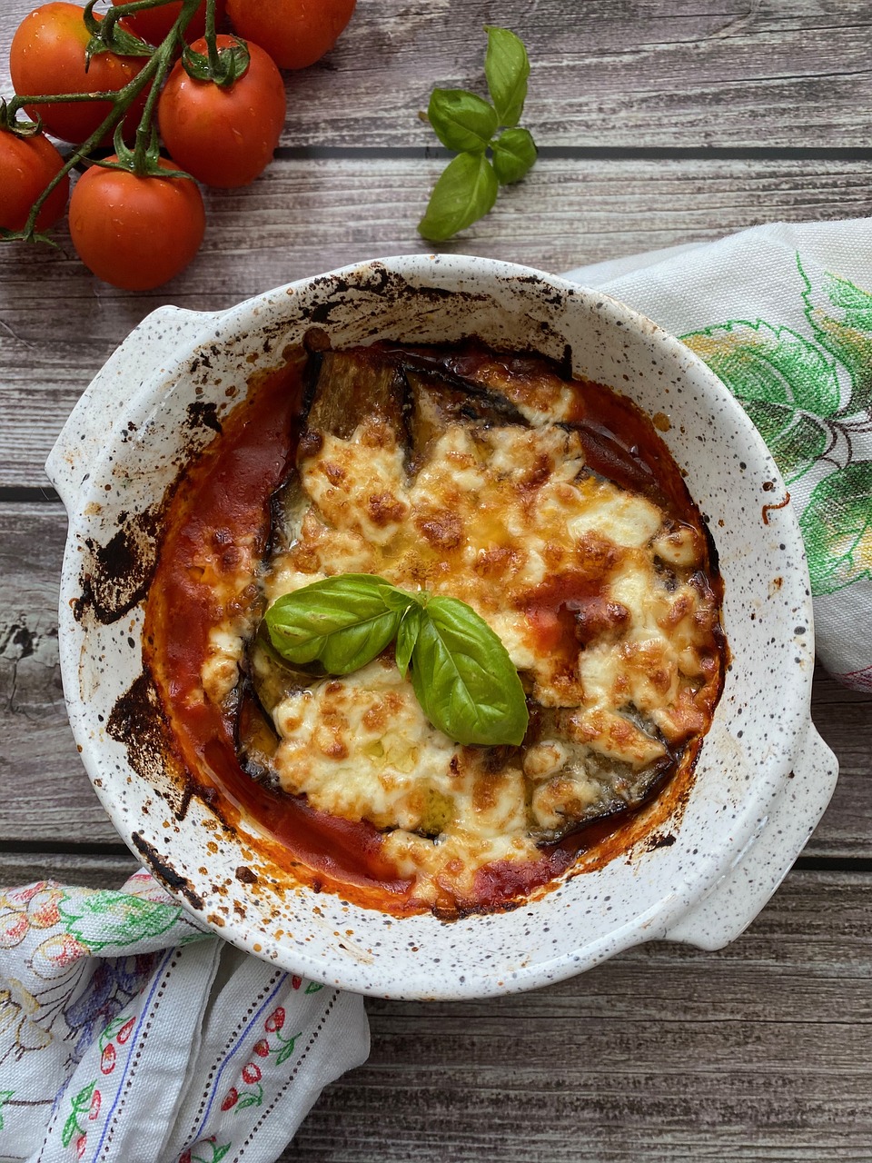 Parmigiana di melanzane al forno con salsa di pomodoro, basilico e formaggio, piatto tipico calabrese adattabile in chiave veg-friendly.