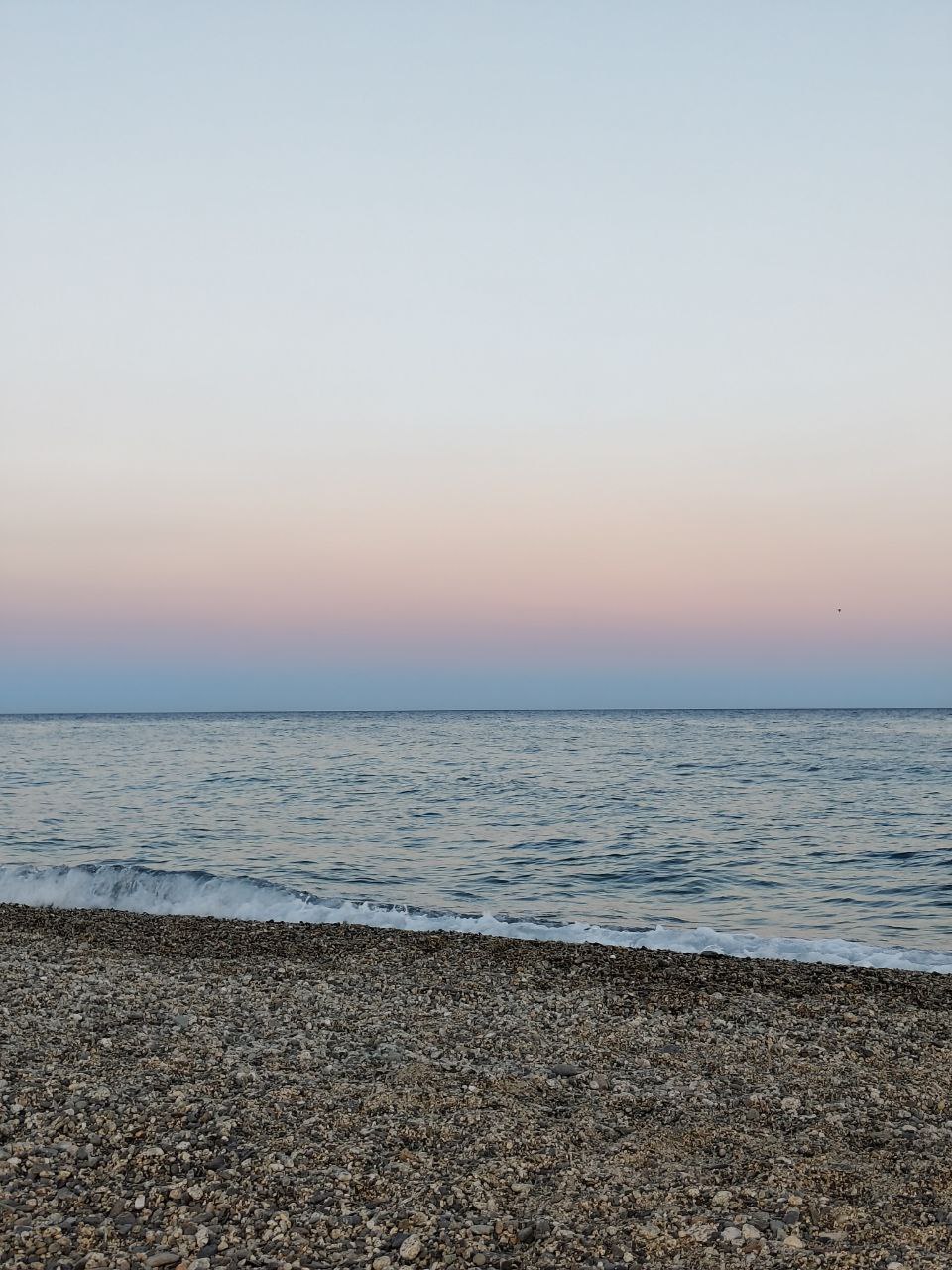 Spiaggia deserta al tramonto con il mare calmo.