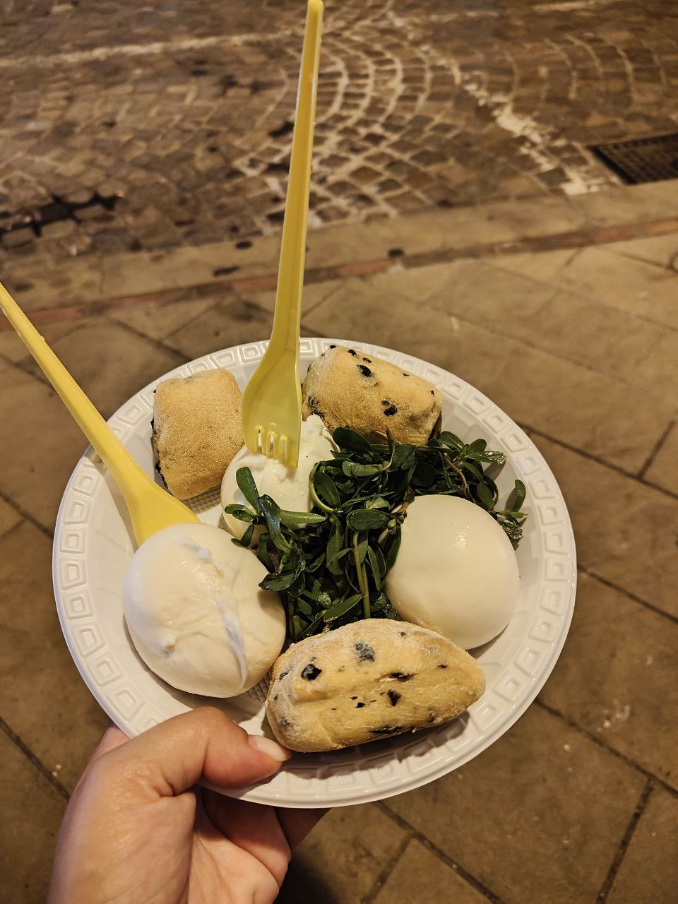 Mozzarella fresca preparata al momento, servita con un panino alle olive e un contorno di insalata mista, piatto tipico delle sagre calabresi.