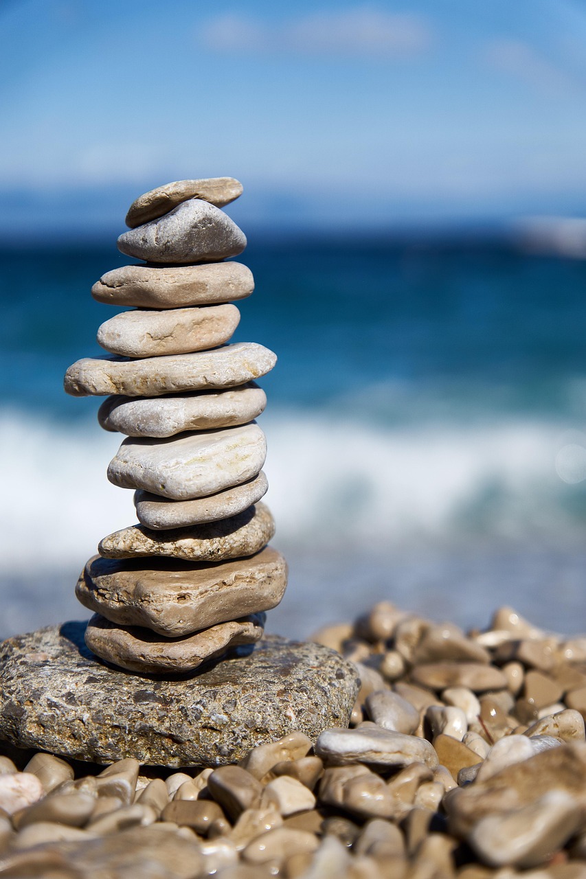 Torre di pietre sulla spiaggia, simbolo di equilibrio e cicli naturali.